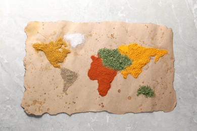 Photo of World map of different spices on light grey marble table, top view