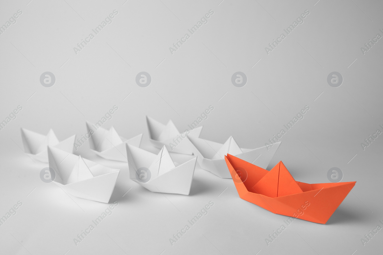 Photo of Group of paper boats following orange one on white background. Leadership concept