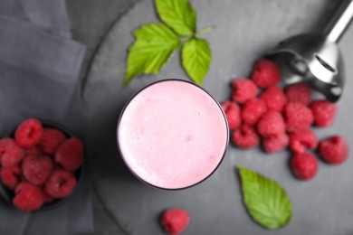 Photo of Glass of tasty raspberry smoothie on dark marble table, flat lay