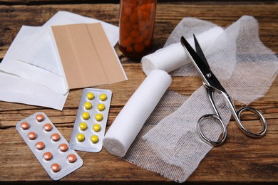 Photo of White bandage rolls and medical supplies on wooden table