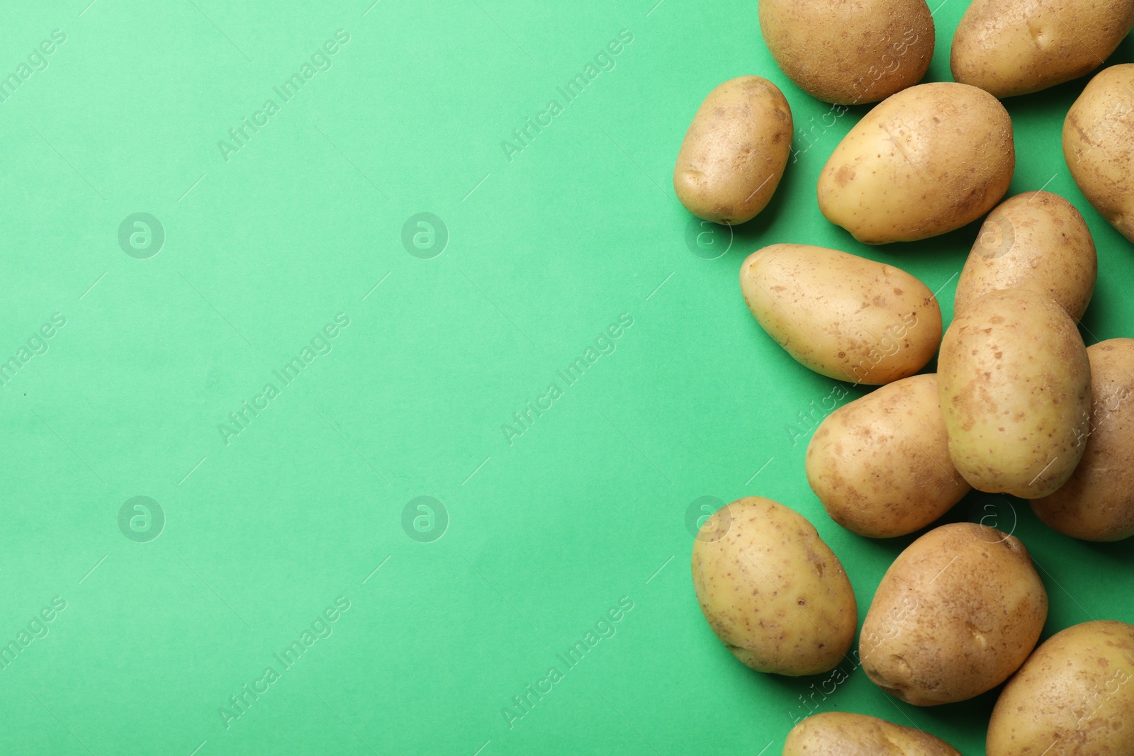 Photo of Fresh raw potatoes on green background, flat lay. Space for text