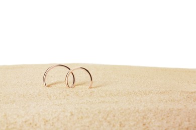 Photo of Honeymoon concept. Two golden rings and sand isolated on white