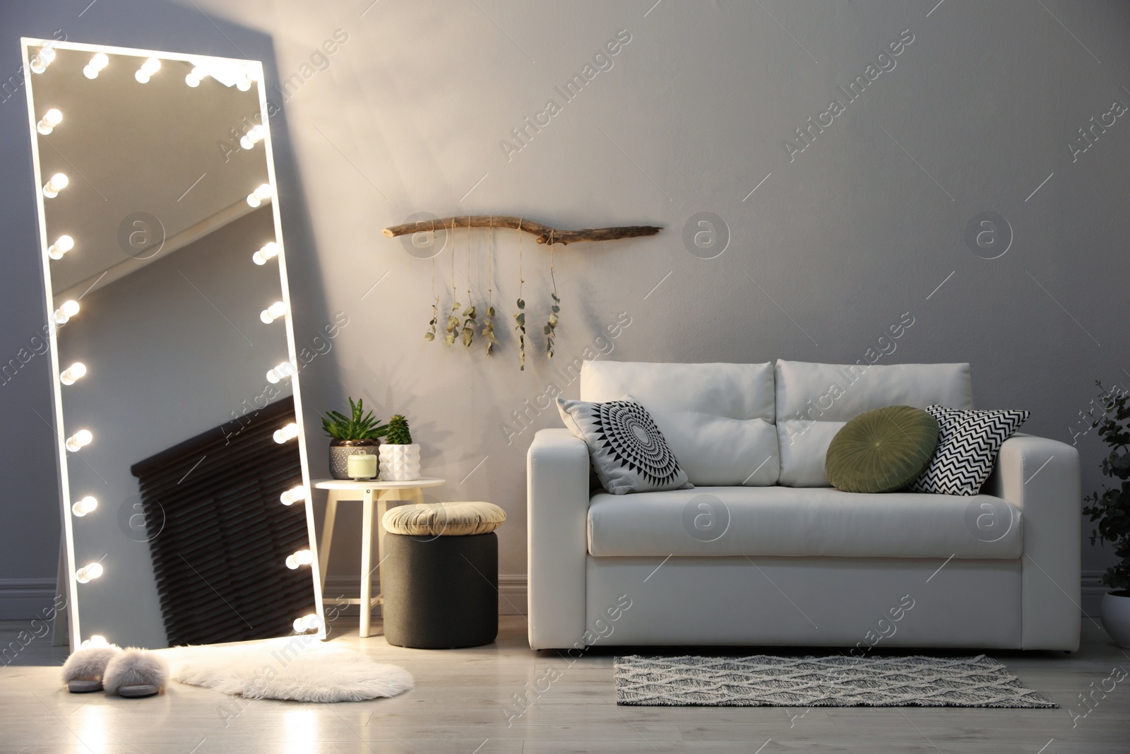 Photo of Stylish mirror with light bulbs and comfortable sofa in living room. Interior design