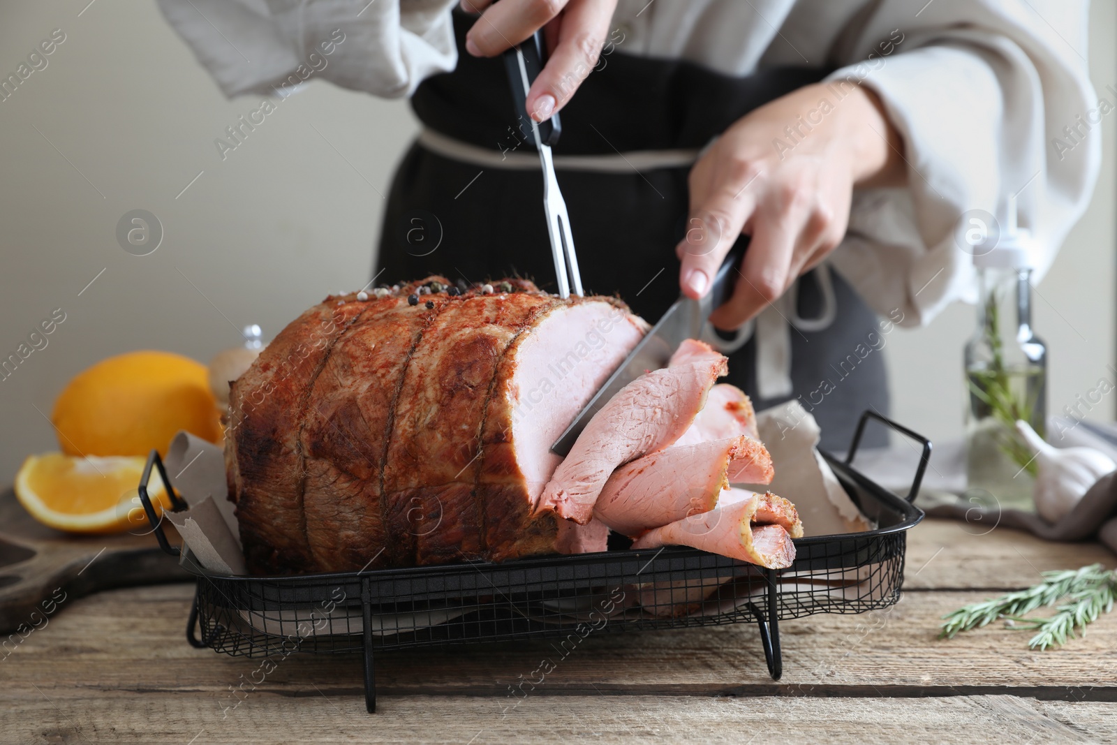 Photo of Woman cutting delicious baked ham at wooden table, closeup