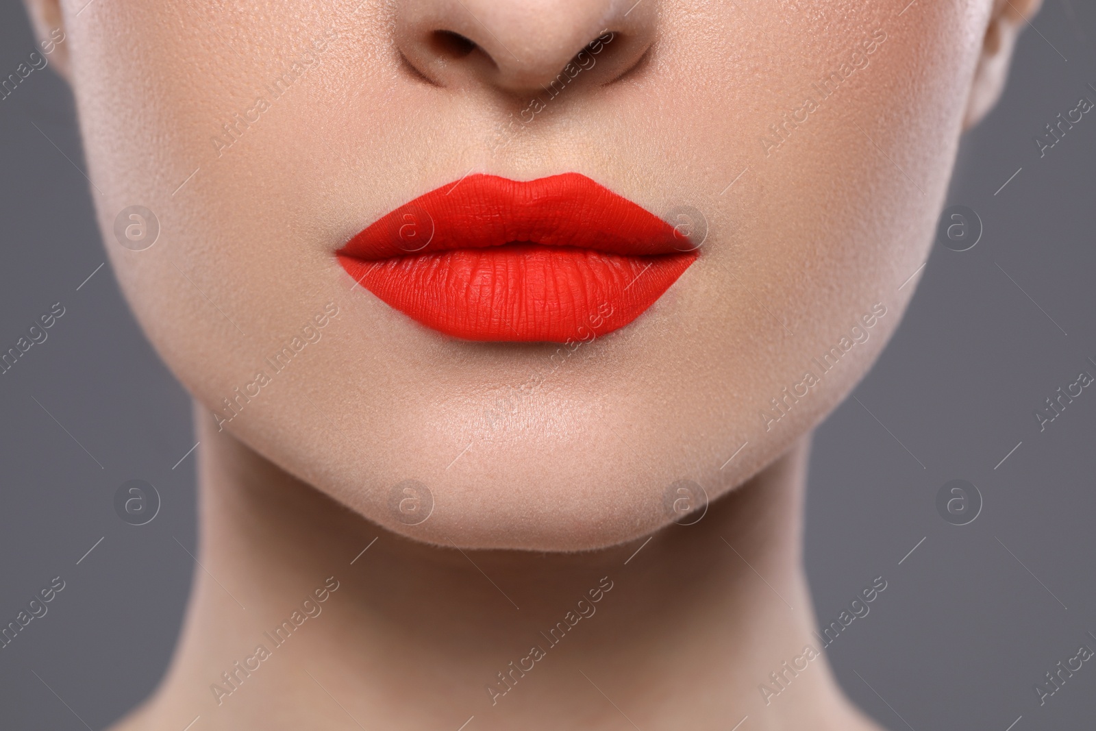 Photo of Young woman with beautiful red lips on grey background, closeup