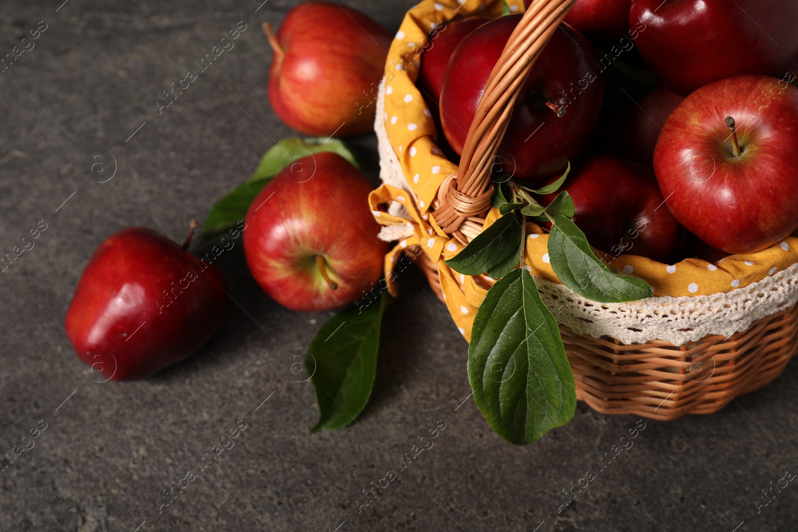 Photo of Ripe red apples and leaves on dark grey table