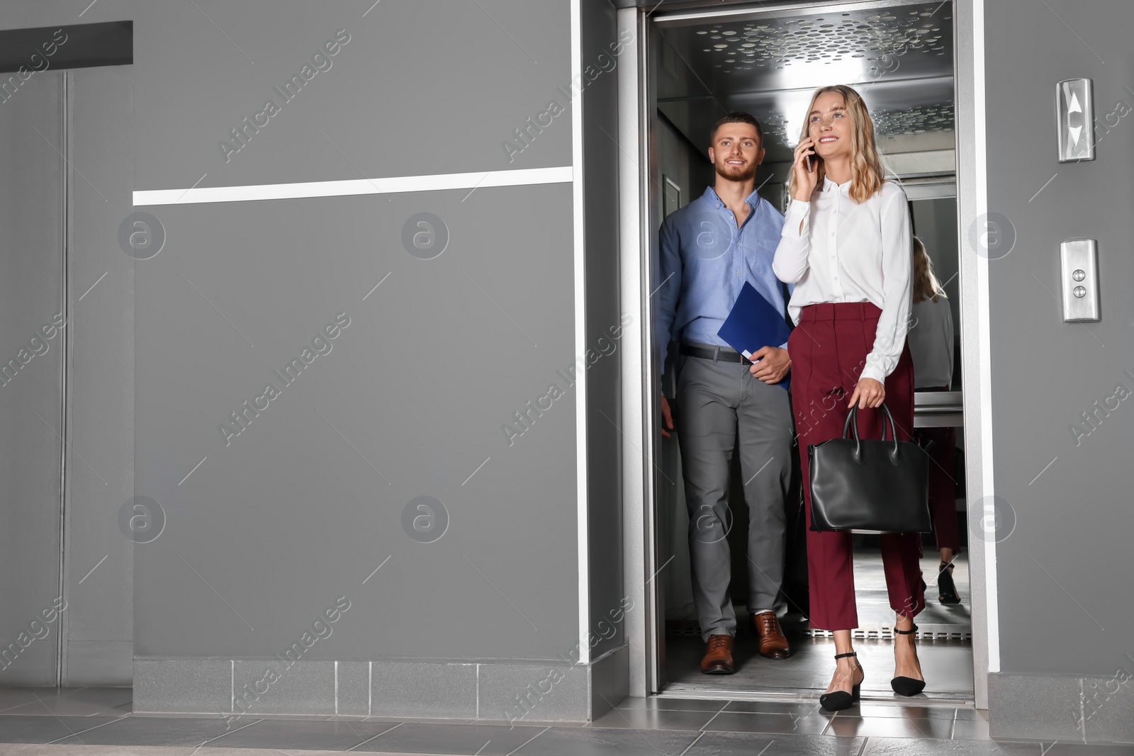 Photo of Colleagues walking out modern elevator in office building