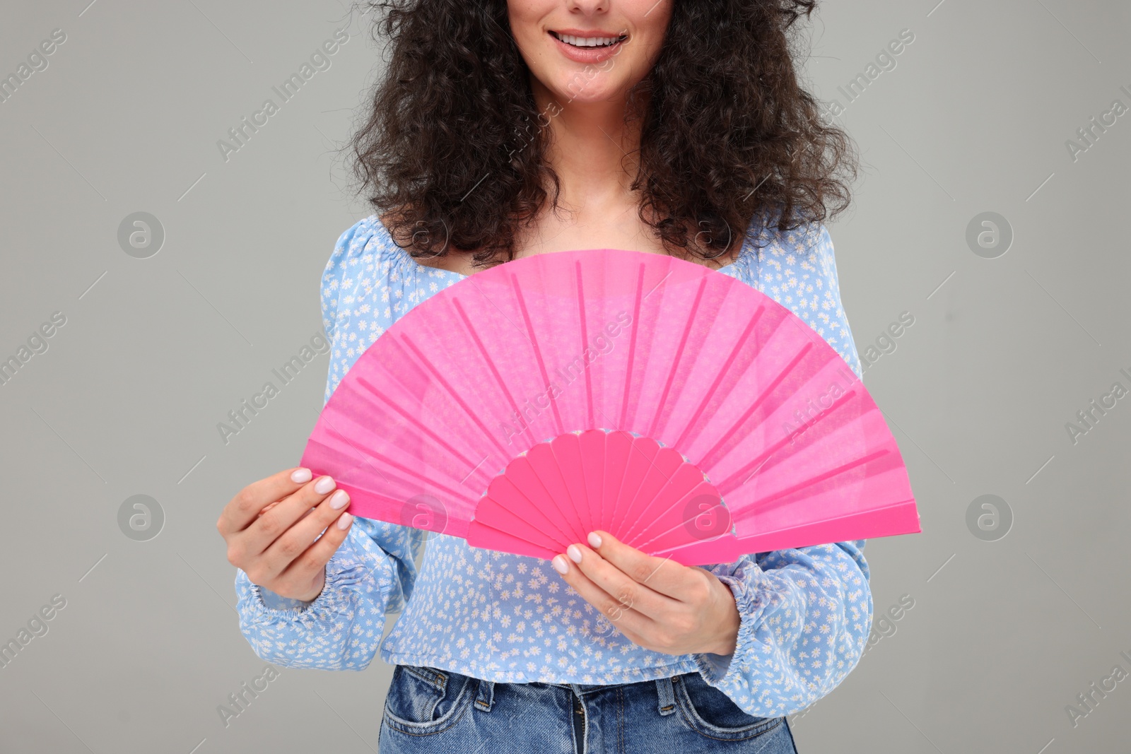 Photo of Woman holding hand fan on light grey background, closeup