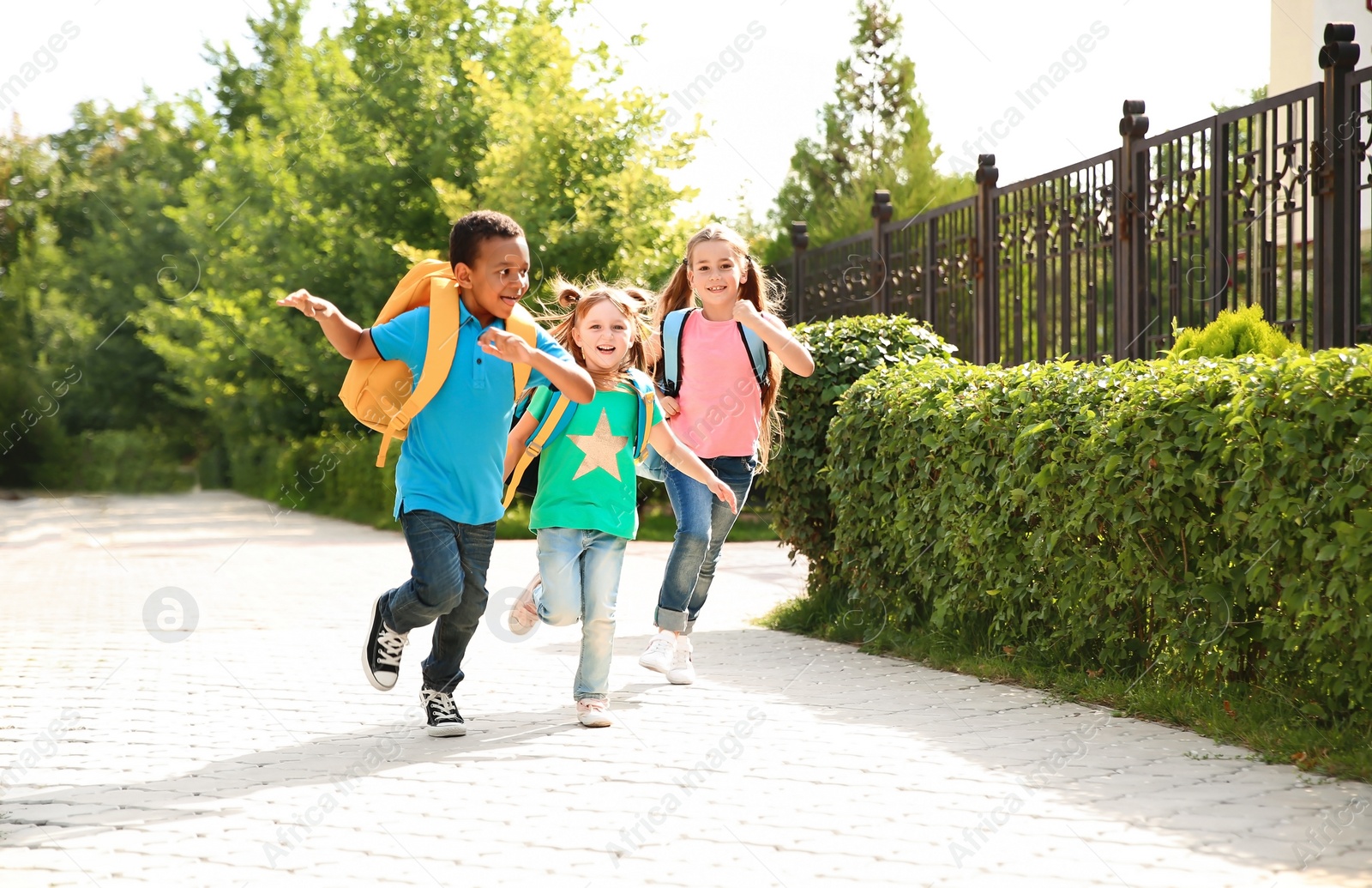 Photo of Cute little children with backpacks running outdoors. Elementary school