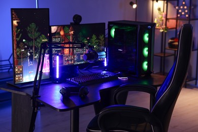 Playing video games. Stylish room interior with modern computer and gaming chair in neon lights