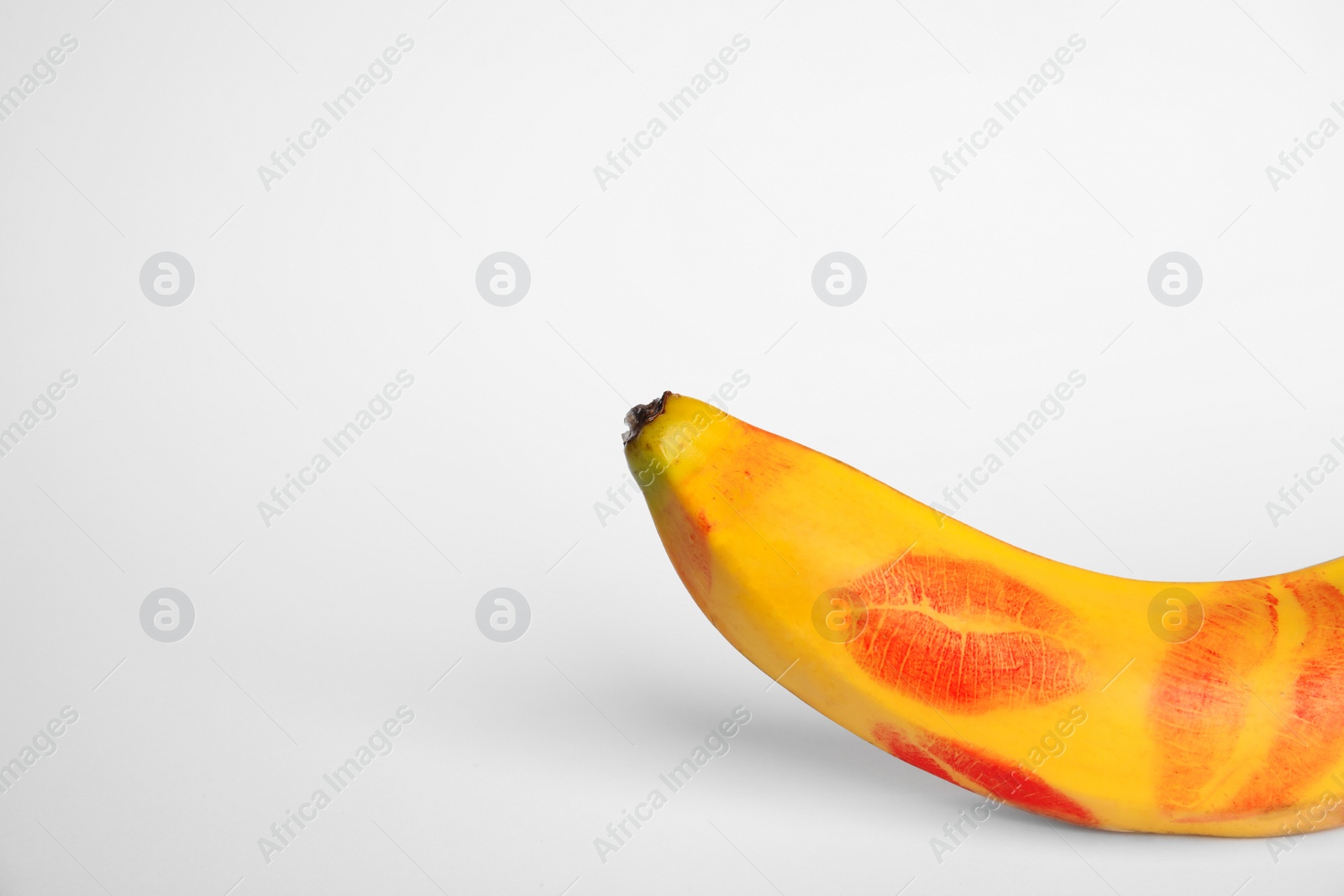 Photo of Fresh banana with red lipstick marks on white background. Oral sex concept