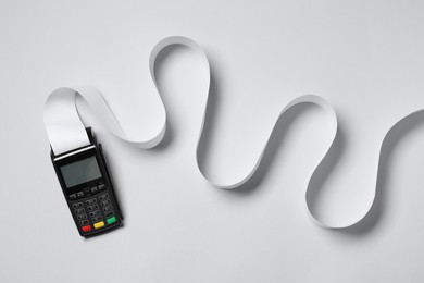 Photo of Payment terminal with thermal paper for receipt on light grey background, top view