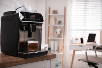 Photo of Modern espresso machine with glass cup of coffee on table in office. Space for text