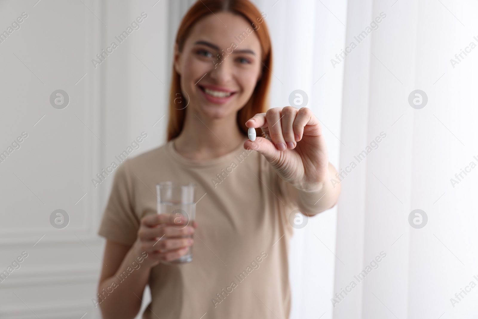 Photo of Beautiful young woman with vitamin pill and glass of water, selective focus