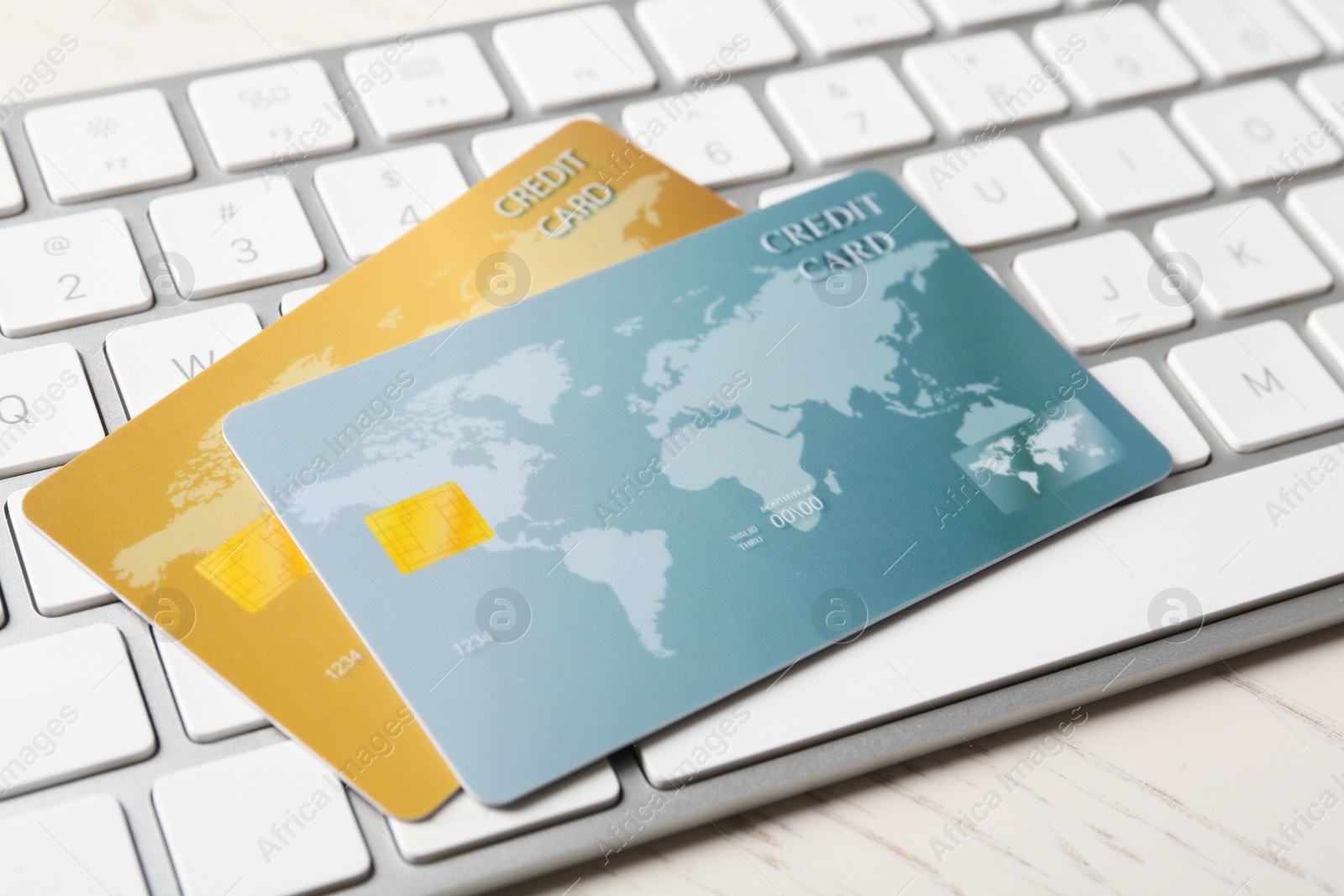 Photo of Online payment. Credit cards and keyboard on white wooden table, closeup