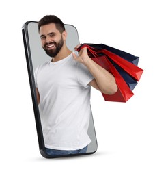 Image of Online shopping. Happy man with paper bags looking out from smartphone on white background