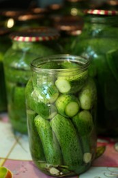 Photo of Pickling jars with fresh cucumbers on table, closeup