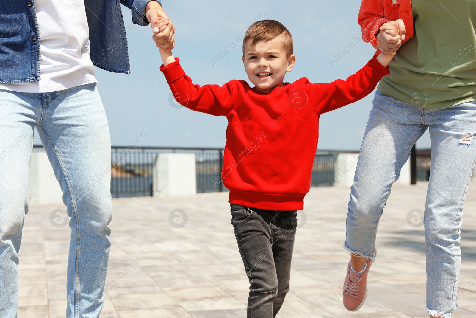 Photo of Happy child having fun with his parents outdoors. Family weekend