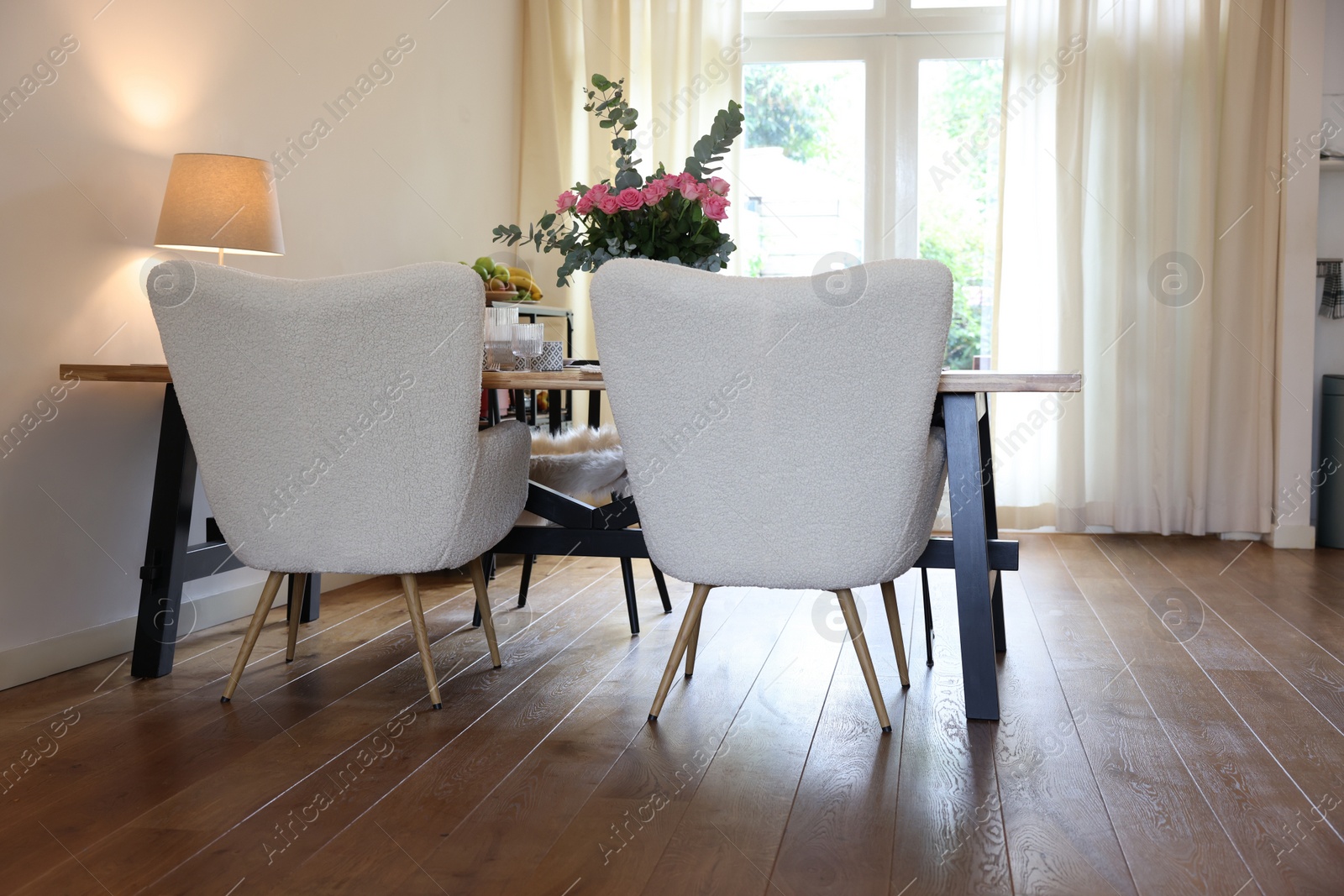 Photo of Stylish dining room with comfortable furniture, big window and bouquet of roses