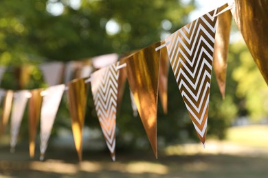 Photo of Golden bunting flags in park. Party decor