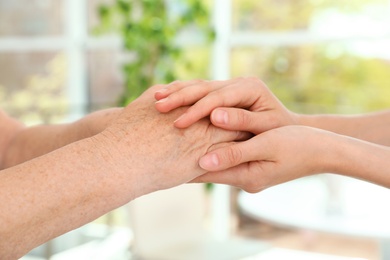 Photo of People holding hands together on blurred background, closeup. Help and elderly care concept