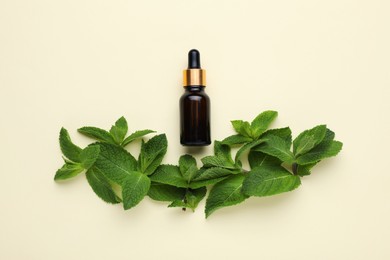 Photo of Bottle of essential oil and mint on beige background, flat lay