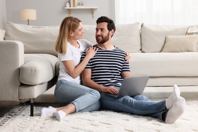 Happy couple with laptop on floor at home