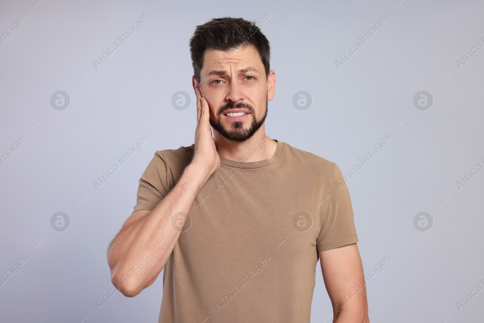 Photo of Man suffering from ear pain on grey background