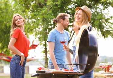 Photo of Young people having barbecue with modern grill outdoors