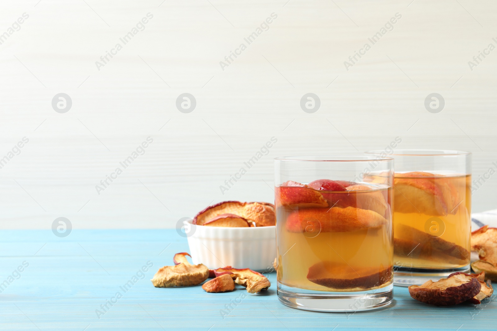 Photo of Delicious compot with dried apple slices on light blue wooden table. Space for text