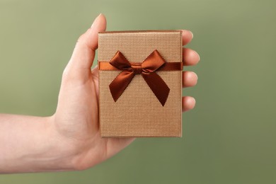 Photo of Doctor holding gift box on olive background, closeup. Medical present