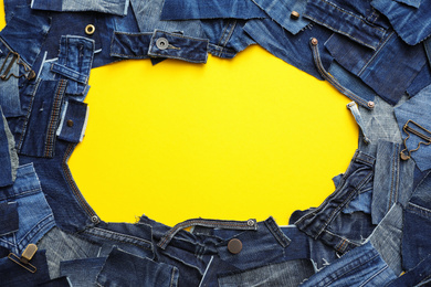 Photo of Frame made of cut jeans on yellow background. Space for text