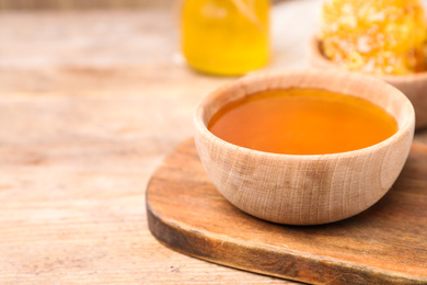 Photo of Tasty aromatic honey in bowl on wooden table