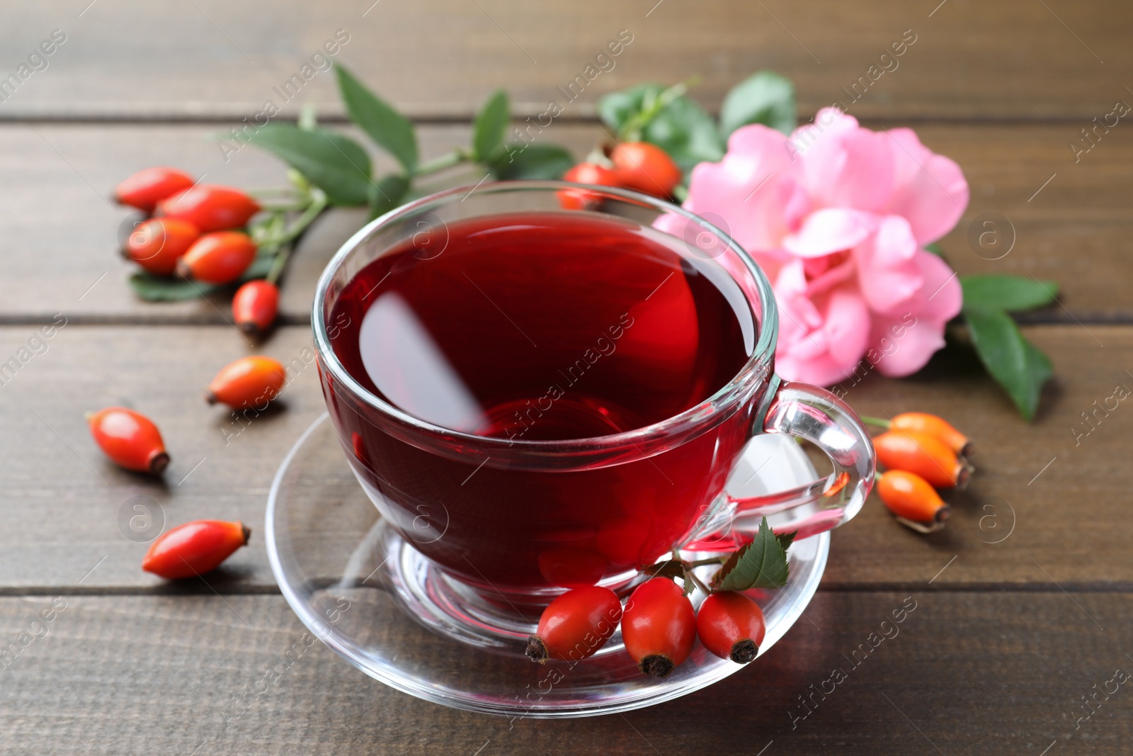 Photo of Aromatic rose hip tea and fresh berries on wooden table