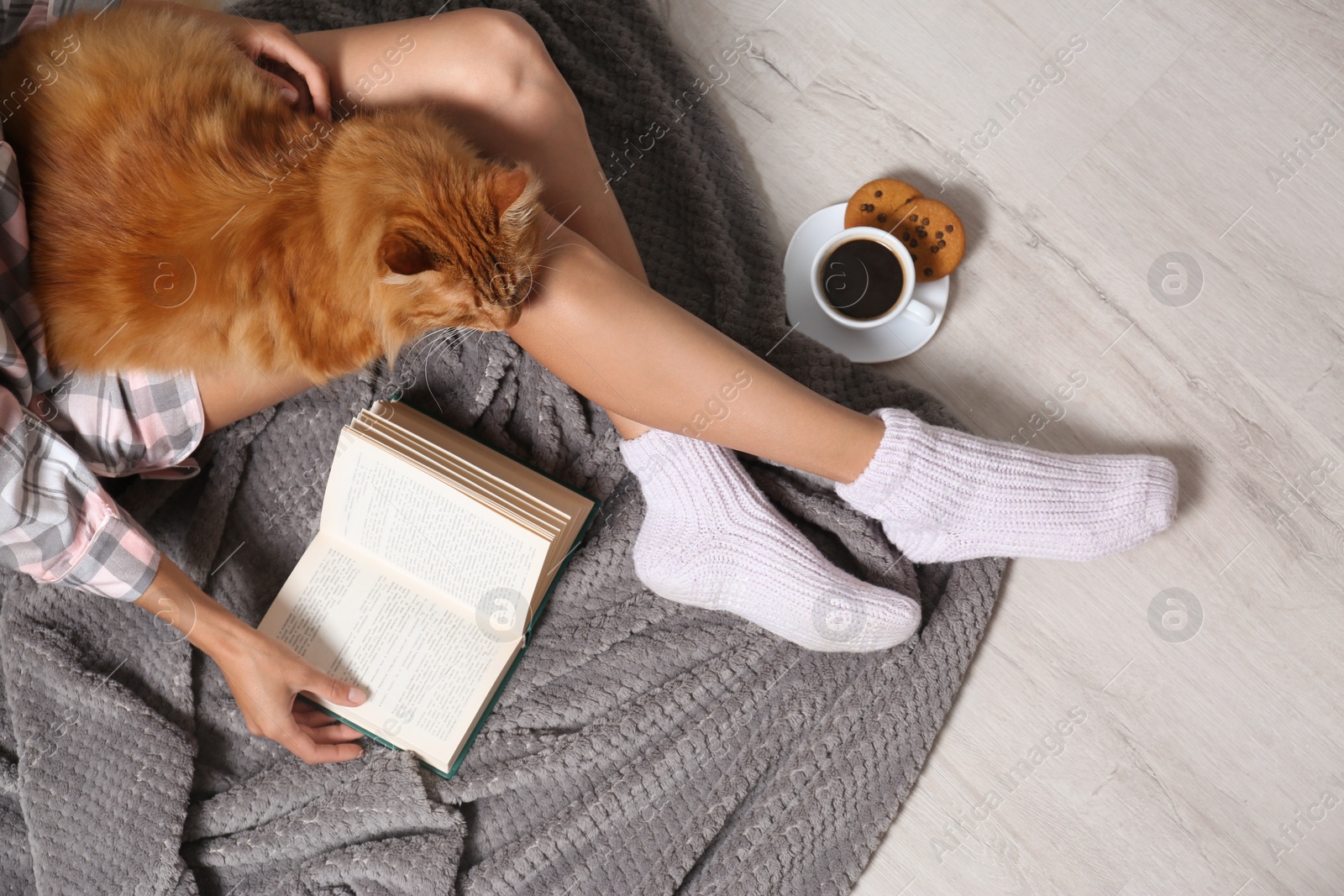 Photo of Woman with cute red cat and book on floor, top view