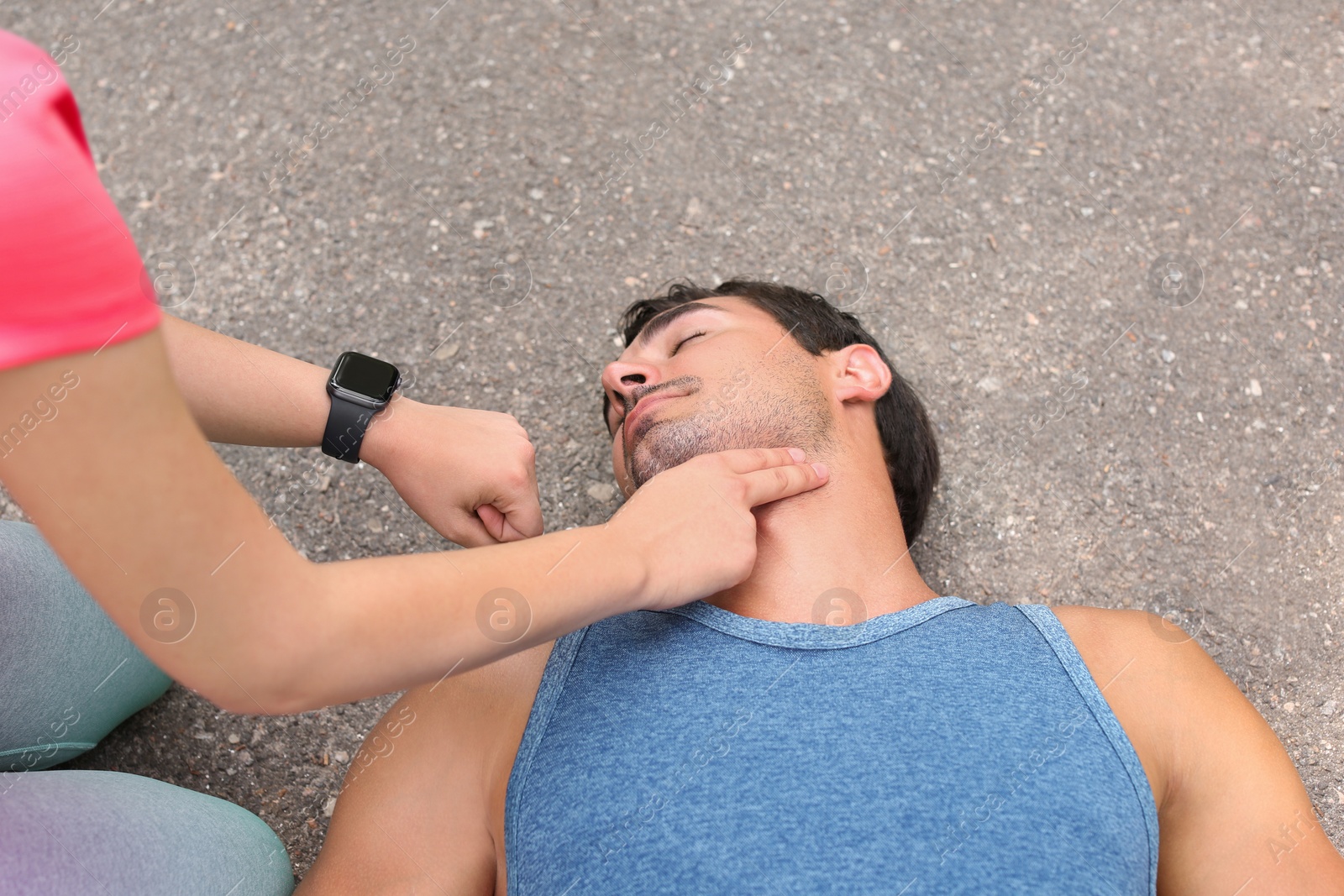 Photo of Young woman checking pulse of unconscious man on street