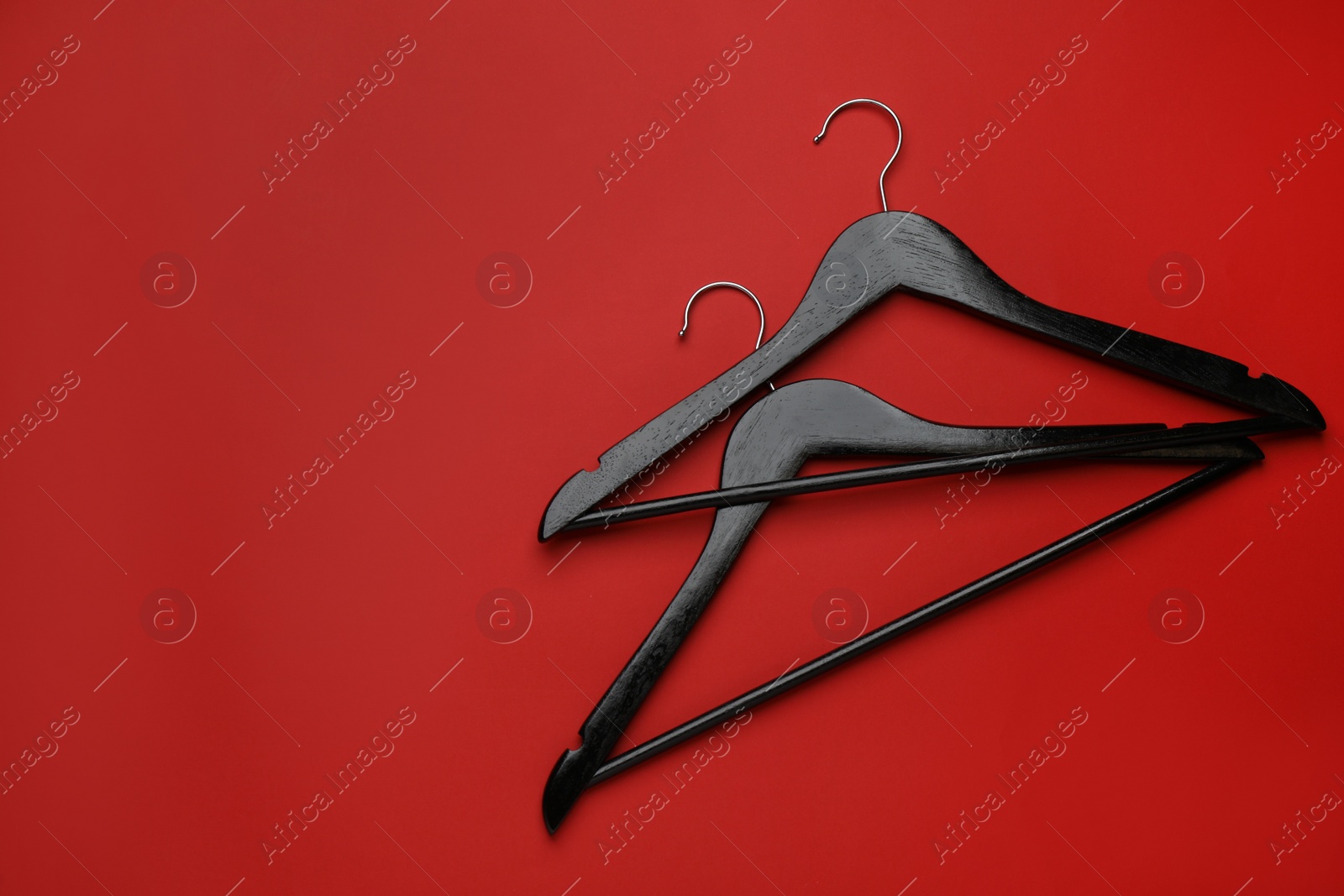 Photo of Empty clothes hangers on red background, flat lay. Space for text