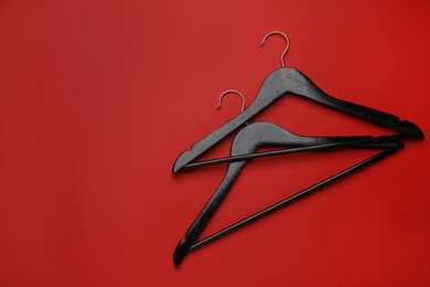 Photo of Empty clothes hangers on red background, flat lay. Space for text