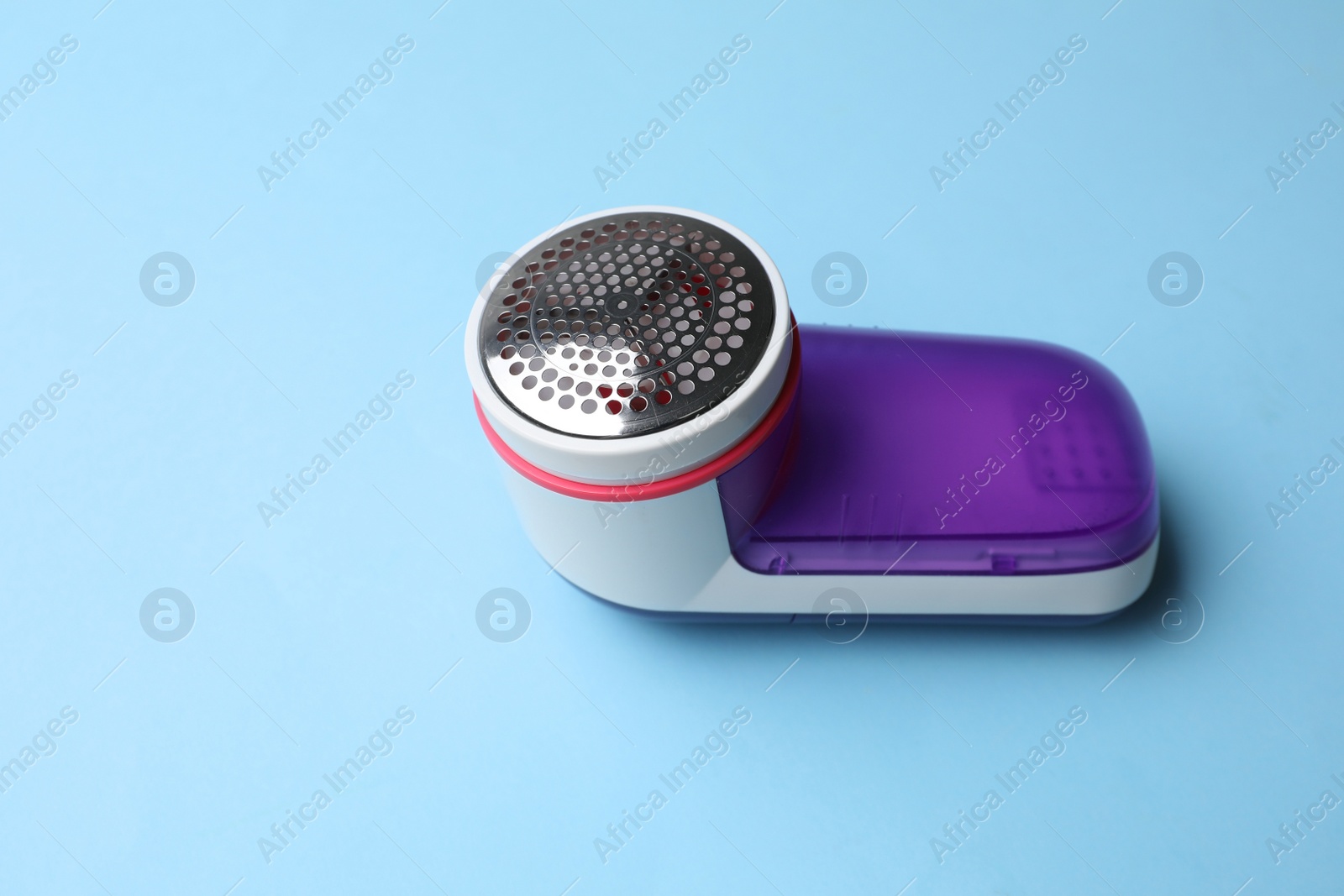 Photo of Modern fabric shaver on light blue background