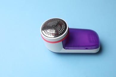 Photo of Modern fabric shaver on light blue background