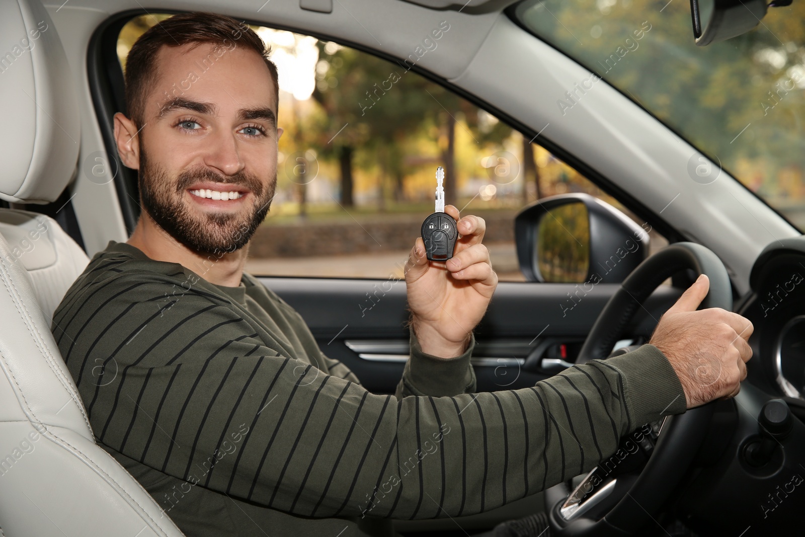 Photo of Young man holding car key in auto. Driving license test