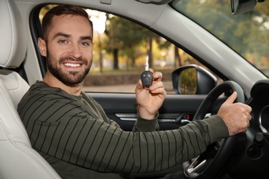 Photo of Young man holding car key in auto. Driving license test