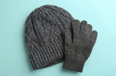 Woolen gloves and hat on light blue background, flat lay