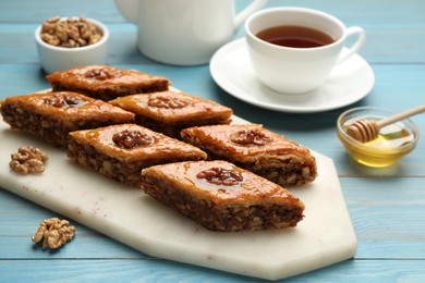 Photo of Delicious sweet baklava with walnuts on turquoise wooden table