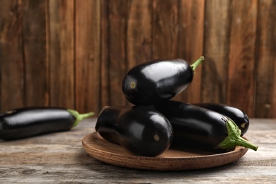 Photo of Plate with raw ripe eggplants on table