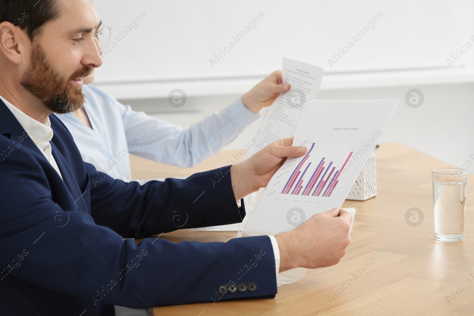 Photo of Businesspeople working with charts at wooden table in office, closeup