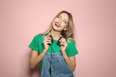 Photo of Beautiful young woman with healthy long blonde hair and headphones on color background