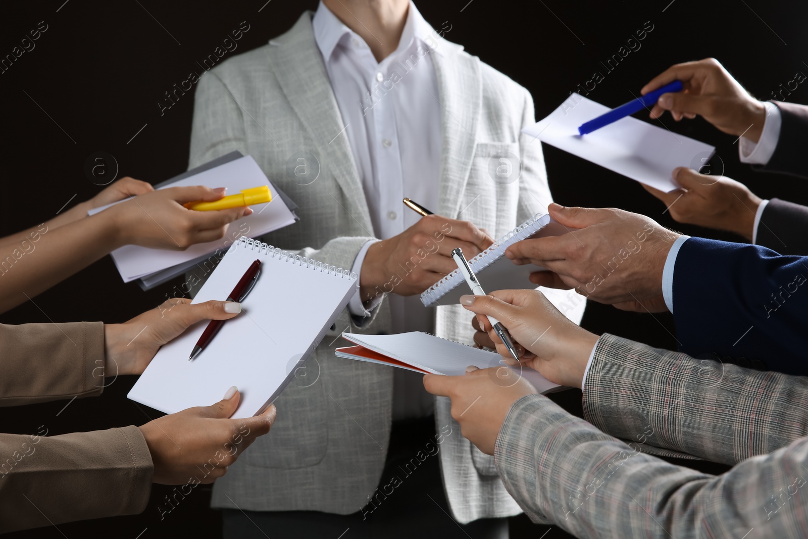 Photo of Man signing autograph in notebooks on black background, closeup