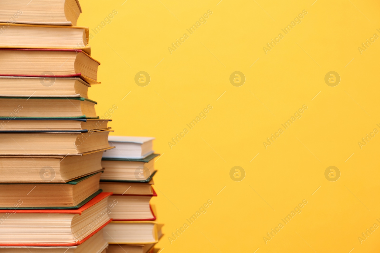 Photo of Many hardcover books on orange background, space for text. Library material