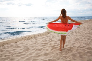 Photo of Beautiful woman with bright beach towel on seashore, back view